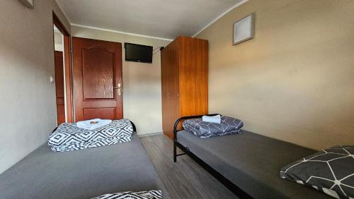 a small room with two beds and a tv at Apartamenty Piekary in Piekary Śląskie