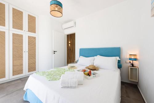 a bedroom with a white bed with a blue headboard at Helen Beach Front Luxury Villas in Kastraki Naxou