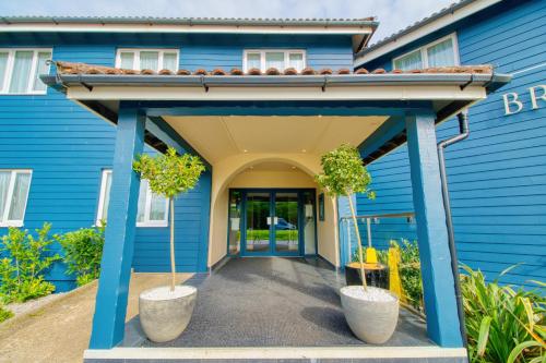 a blue house with two potted trees in front of it at The Bridge House; BW Signature Collection in Ferndown