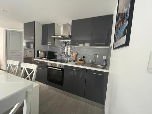 - une cuisine avec des placards noirs, un évier et un comptoir dans l'établissement Maison du circuit - Hunaudières, à Mulsanne