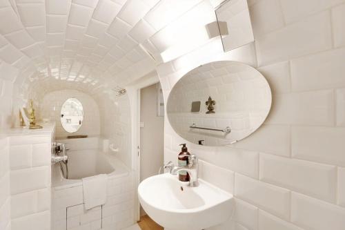une salle de bain blanche avec un lavabo et un miroir dans l'établissement Classy Bourgeois - Chic 2 Bedroom Apt in Le Marais, à Paris