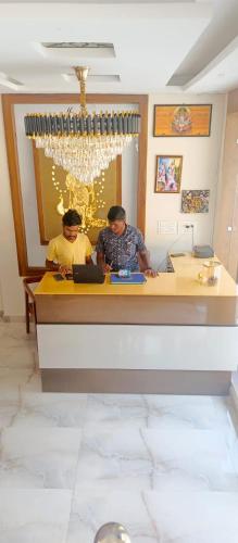 two men sitting at a counter with a laptop at HOTEL POLL STAR Inn in Barkot