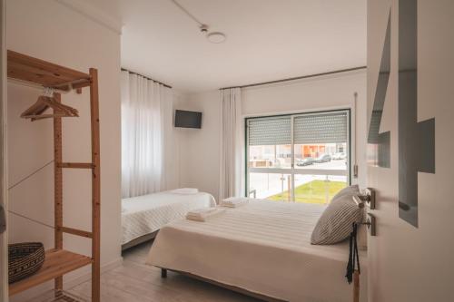 a bedroom with two beds and a window at Paredes Surf House in Pataias
