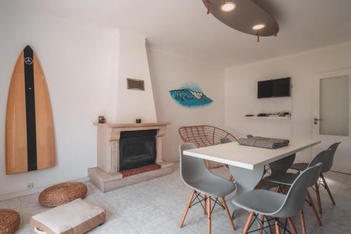 a dining room with a table and chairs and a fireplace at Paredes Surf House in Pataias