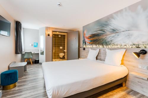 a bedroom with a white bed and a painting on the wall at Kyriad Direct Tours Sud - Chambray Lès Tours in Chambray-lès-Tours