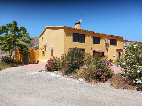 a yellow house with flowers in front of it at Casa rural los Cerezos in Albox