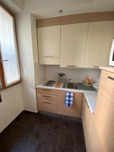 Una pequeña cocina con gabinetes blancos y un fregadero. en Appartamento Milano IEO Prada, en Vigentino