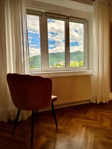 a chair sitting in front of a window at Cloos - Elegant Residence with Panoramic View in Braşov