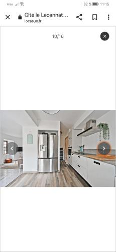 une cuisine avec des armoires blanches et un réfrigérateur en acier inoxydable dans l'établissement Gite le leoannatim, à Ruoms