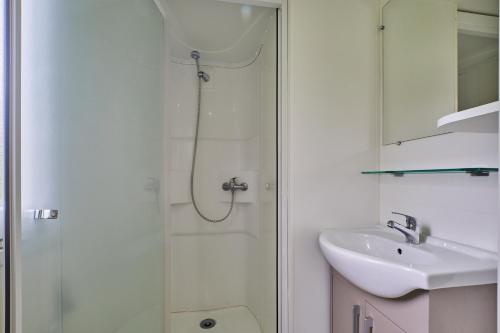 baño blanco con ducha y lavamanos en Mobil Home 4 personnes 207, en Mens