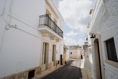 an alley with white buildings and a balcony at Palazzo D'Azeglio in Alberobello