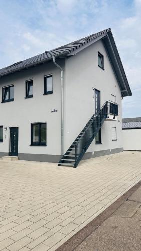 a white house with a staircase on the side of it at AMAO Obsidian - 120 m2 Business & Family Apartment - 3 Bedrooms - 8 Guests - King-Size Beds in Schwanau