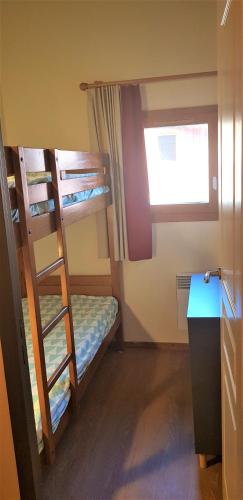une chambre avec deux lits superposés et une fenêtre dans l'établissement Appartement T3 au pied des pistes Les Coches, à La Plagne Tarentaise