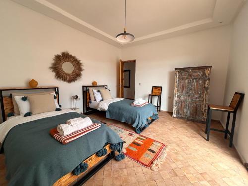 Villa Essaouira petit déjeuner compris في الصويرة: غرفة نوم بسريرين ومرآة على الحائط