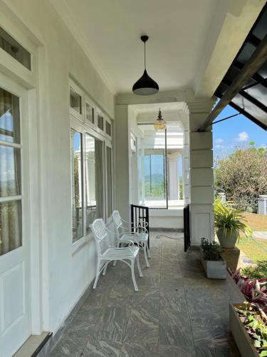 a porch with white chairs and windows on a house at Rose Hill Bungalow in Gampola