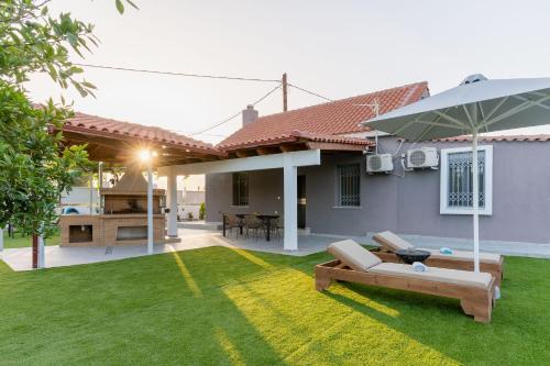 a house with a lawn with a couch and an umbrella at Private Pool Retreat - Georgia's Garden Oasis in Alónia