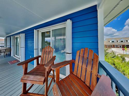 two chairs sitting on the front porch of a blue house at Happy Days in Surf City