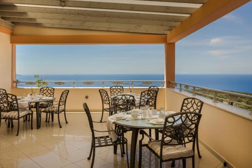 a restaurant with tables and chairs on a balcony at Belle View Hotel - Sea View & Sunset in Mánganos