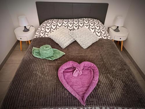 - un lit avec un cœur rose et des serviettes dans l'établissement Chez Fifi au Barcarès, au Barcarès
