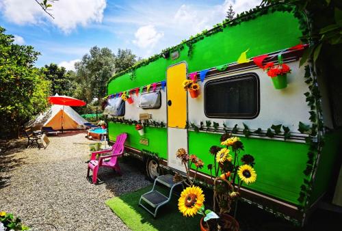 a green and white rv parked next to a tent at Caravan of Love by Casa das Artes in Luz de Tavira