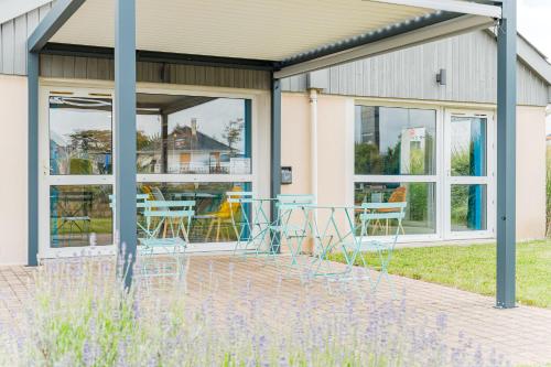 a patio with chairs and tables in front of a building at Kyriad Direct Tours Sud - Chambray Lès Tours in Chambray-lès-Tours