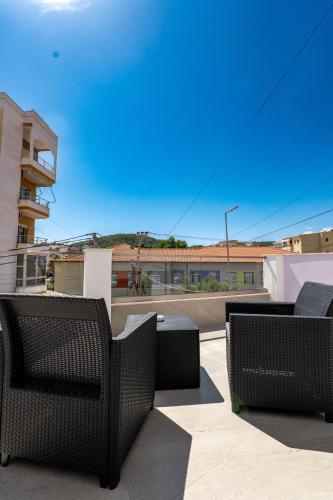 a group of chairs on a patio with a building at Fori's rooms in Himare