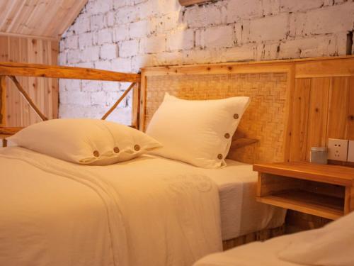 a bedroom with a white bed with a wooden headboard at 张家界竹奢民宿 in Zhangjiajie