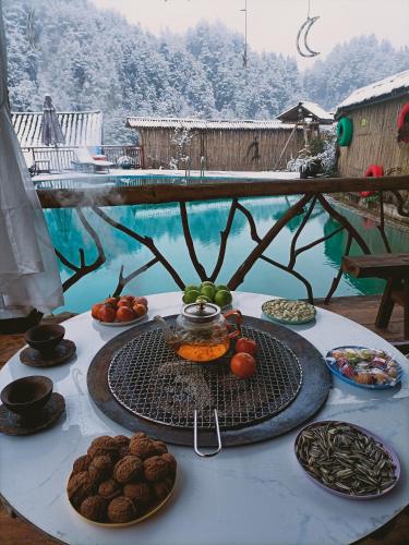 a table with plates of food on a table with a pool at 张家界竹奢民宿 in Zhangjiajie