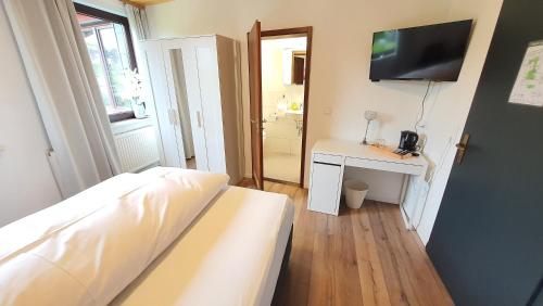 a bedroom with a bed and a desk with a television at Hotel Schneiderhof in Braunlage