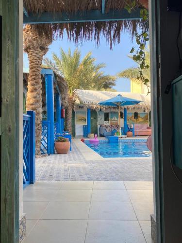 a resort with a swimming pool with palm trees and umbrellas at Chillax Dahab in Dahab