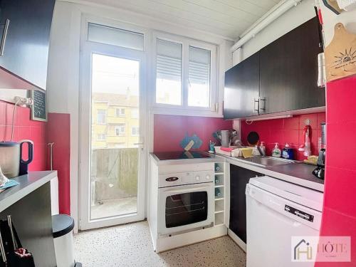 une cuisine rose avec une cuisinière blanche four supérieur dans l'établissement Balcon Marin des Peupliers, à Bray-Dunes