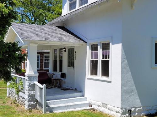a white house with a porch and a staircase at Oscoda Hilltop Haven - Great Location Near Beach! in Oscoda