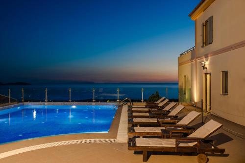 a swimming pool with lounge chairs next to a building at Belle View Hotel - Sea View & Sunset in Mánganos