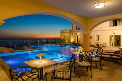 a hotel patio with a pool and tables and chairs at Belle View Hotel - Sea View & Sunset in Mánganos