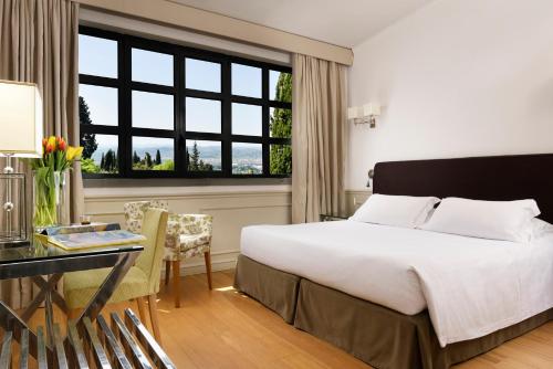a hotel room with a bed and a desk and a window at FH55 Hotel Villa Fiesole in Fiesole