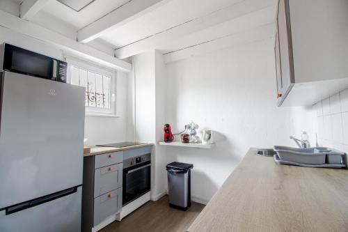 La cuisine blanche est équipée d'un évier et d'un réfrigérateur. dans l'établissement Duplex Centre de Metz, 2 chambres, à Metz