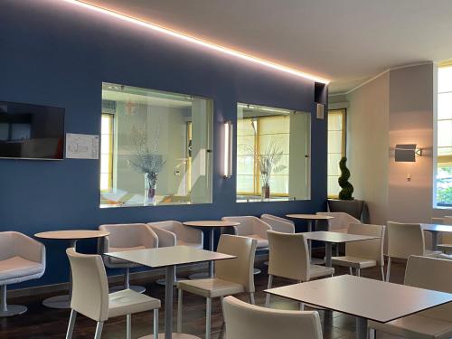 a dining room with tables and white chairs at Holiday Inn Express Milan-Malpensa Airport by IHG in Case Nuove