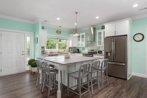 a kitchen with a large island with chairs and a refrigerator at Voyage Anchor in Nags Head