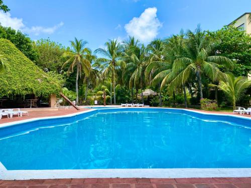a blue swimming pool with palm trees in the background at Villas Tropical By Andiani in Cancún