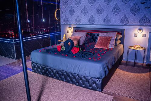 une chambre avec un grand lit avec des fleurs rouges dessus dans l'établissement ROMANCE ROOM & LOVE - JACUZZI - PARKING - Menton, à Menton