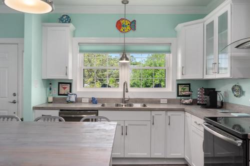 a kitchen with white cabinets and a window at Voyage Anchor in Nags Head