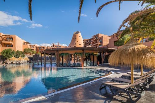 einen Pool in einem Resort mit Stühlen und Sonnenschirmen in der Unterkunft Barceló Tenerife in San Miguel de Abona