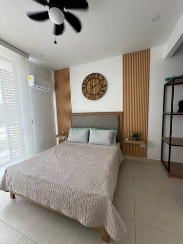 a bedroom with a bed and a clock on the wall at Apartaestudio en Pozos Colorados in Playa Bello Horizonte