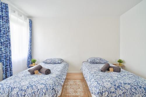 deux lits dans une chambre avec literie bleue dans l'établissement Le Gabriel - Maison spacieuse et calme près de Paris, à Cormeilles-en-Parisis