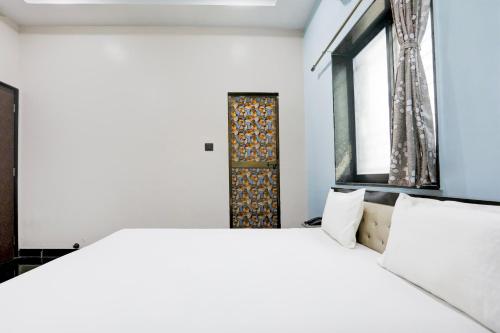 a bedroom with a large white bed and a window at OYO Hotel Raj Guest House in Akola