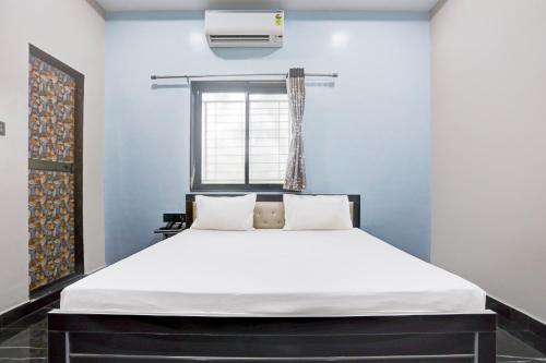 a bedroom with a large white bed with a window at OYO Hotel Raj Guest House in Akola