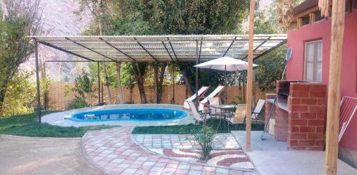 een patio met een parasol en een zwembad bij Cabaña en Valle de Elqui in Horcon