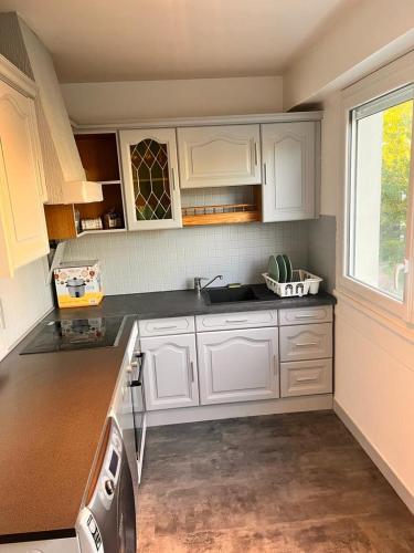 une cuisine avec des armoires blanches et une fenêtre dans l'établissement Spacieux et Moderne - proche de paris, Évry-Courcouronnes