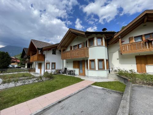 a house with wooden balconies and a yard at Residence Valentino in Pinzolo