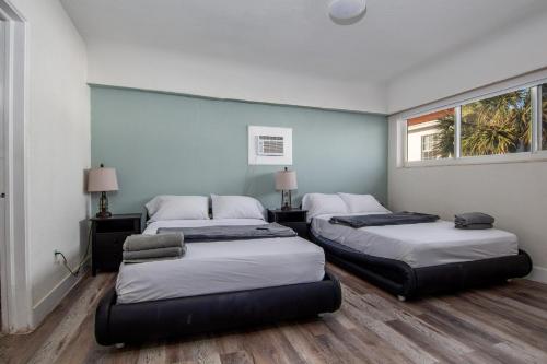 two beds in a room with two windows at Pousada suites in Hollywood